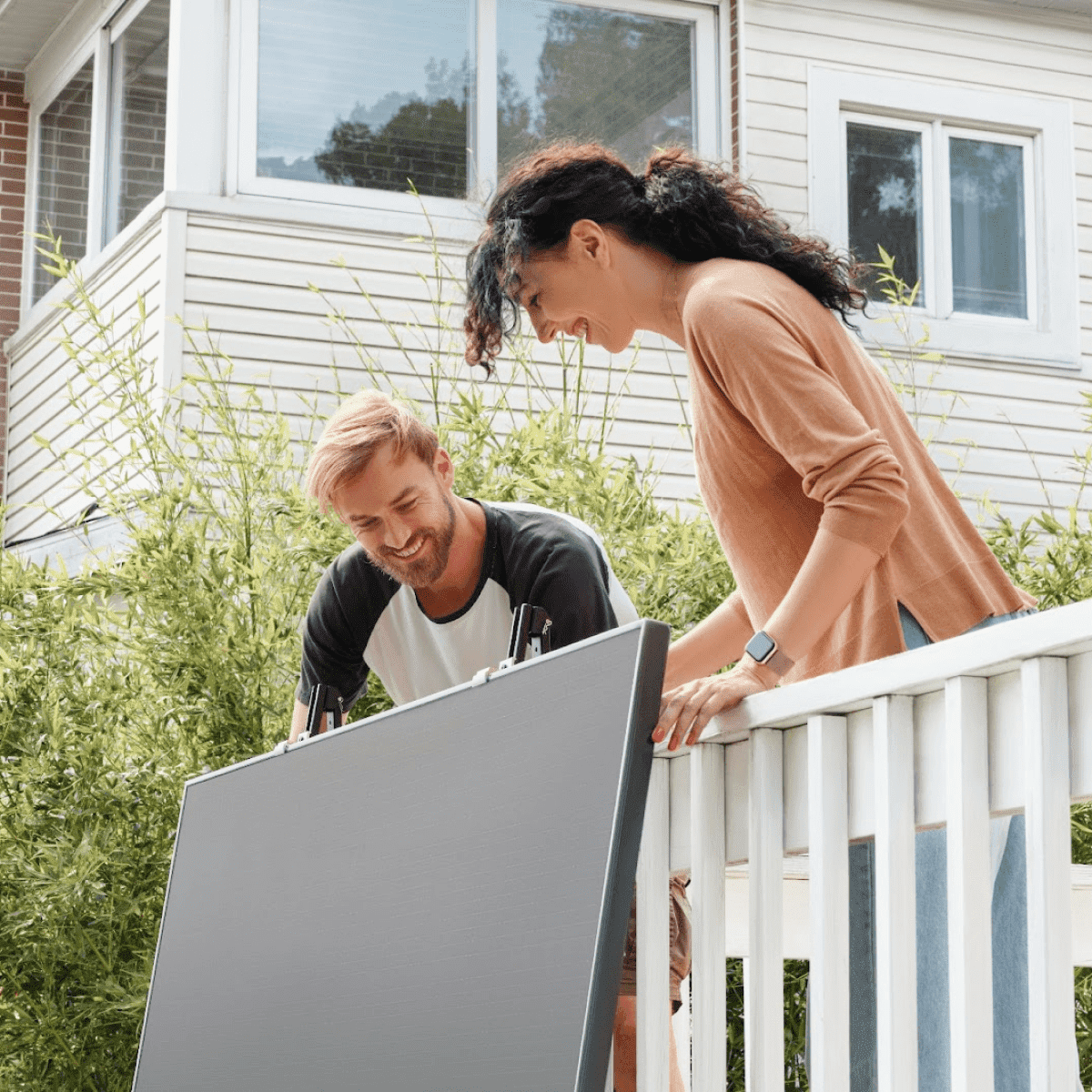 A man and a woman installing a solar panel on their balcony