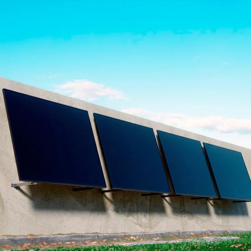 Four solar panels mounted on a wall with a clear blue sky in the background.